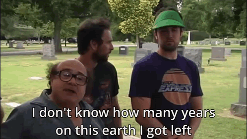 A Group Of Men Are Standing In A Cemetery And One Of Them Is Wearing A Green Hat GIF
