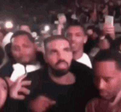 A Group Of Men Are Standing In A Crowd Holding Their Cell Phones . GIF