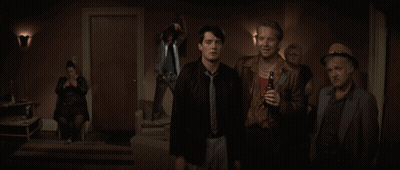 A Group Of Men Are Standing In A Dark Room And One Of Them Is Holding A Bottle Of Beer GIF