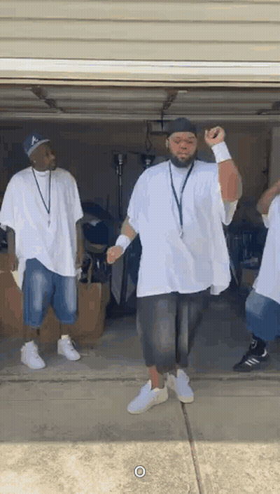 A Group Of Men Are Standing In A Garage Dancing Together . GIF