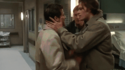 A Group Of Men Are Standing In A Hallway And One Of Them Is Holding Another Man 'S Face GIF