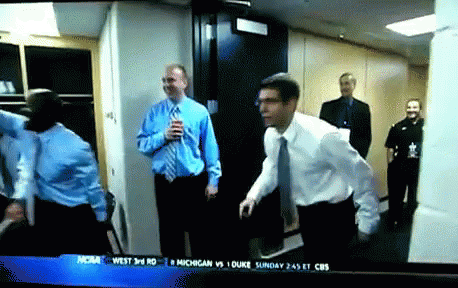 A Group Of Men Are Standing In A Hallway With A Cbs News Headline On The Screen GIF