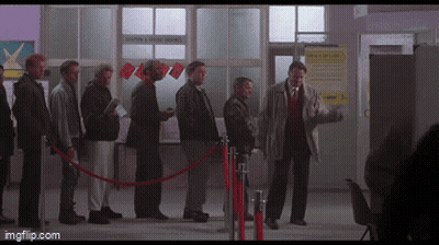 A Group Of Men Are Standing In A Line Behind A Red Rope And A Sign That Says " Moving & Storage " GIF
