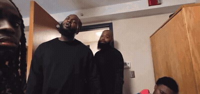 A Group Of Men Are Standing In A Room And One Of Them Has Dreadlocks GIF