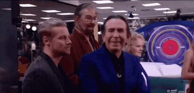 A Group Of Men Are Standing In A Room With A Large Target In The Background . GIF