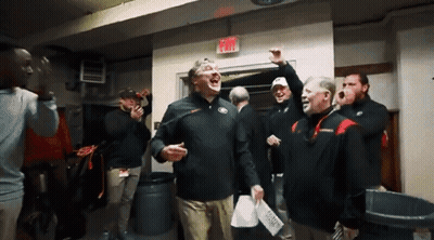 A Group Of Men Are Standing In A Room With An Exit Sign Above Them GIF