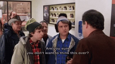 A Group Of Men Are Standing In A Store Talking To Each Other And One Of Them Is Holding A Bottle Of Beer . GIF