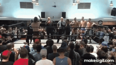 A Group Of Men Are Standing In A Wrestling Ring With A Crowd Watching GIF