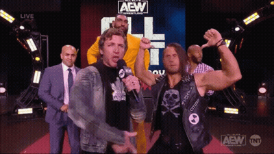 A Group Of Men Are Standing In Front Of A Aew Sign GIF