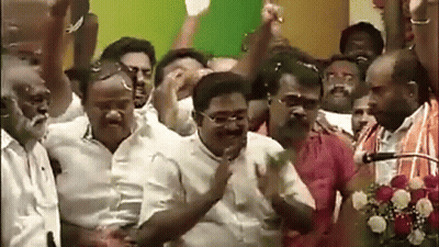 A Group Of Men Are Standing In Front Of A Microphone With Their Arms In The Air GIF