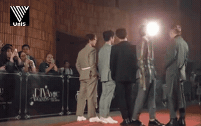 A Group Of Men Are Standing In Front Of A Podium That Says Uni5 GIF