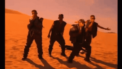 A Group Of Men Are Standing In The Sand In A Desert GIF