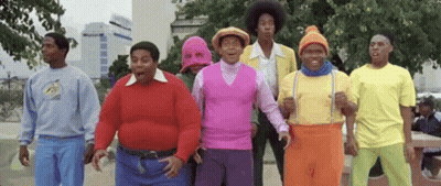 A Group Of Men Are Standing Next To Each Other In A Park Wearing Colorful Outfits . GIF