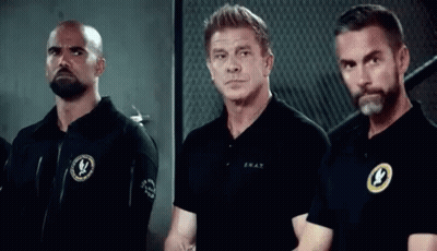 A Group Of Men Are Standing Next To Each Other In A Room . GIF