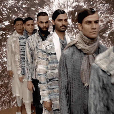 A Group Of Men Are Standing Next To Each Other In Front Of A Sign That Says Lakme Fashion Week Next GIF