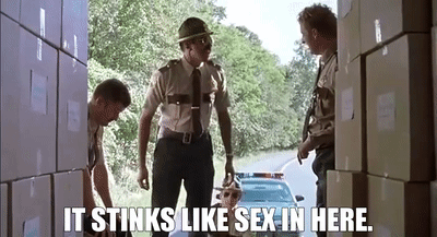 A Group Of Men Are Standing Next To Each Other In Front Of A Stack Of Boxes And A Police Car . GIF
