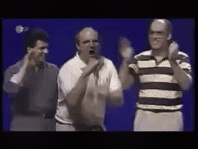 A Group Of Men Are Standing Next To Each Other On A Stage And Applauding . GIF