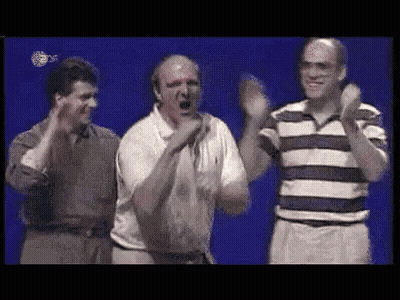 A Group Of Men Are Standing Next To Each Other On A Stage And Clapping Their Hands . GIF