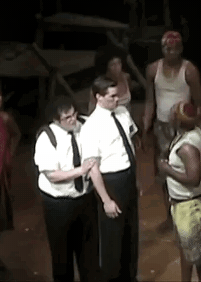 A Group Of Men Are Standing Next To Each Other On A Stage In A Dark Room . GIF