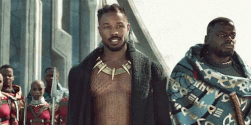 A Group Of Men Are Standing Next To Each Other On A Street . GIF