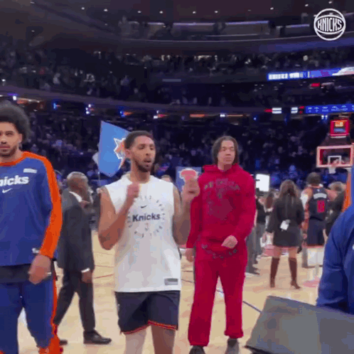 A Group Of Men Are Standing On A Basketball Court . One Of The Men Is Wearing A Knicks Jersey . GIF