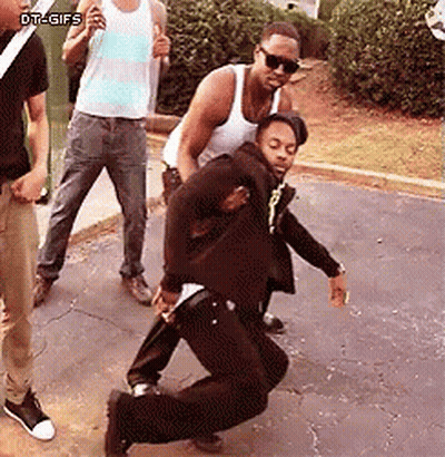 A Group Of Men Are Standing On A Sidewalk And One Of Them Is Dancing . GIF