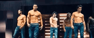 A Group Of Men Are Standing On A Stage Without Shirts . GIF
