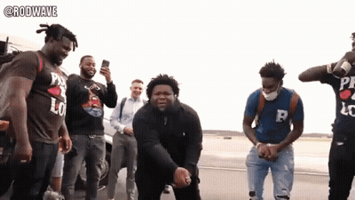 A Group Of Men Are Standing On A Street And One Of Them Is Wearing A Shirt That Says Rodwave GIF
