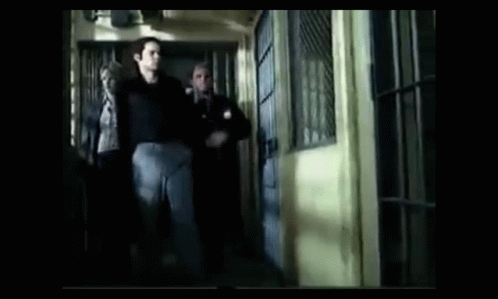 A Group Of Men Are Walking Down A Hallway In A Jail Cell GIF