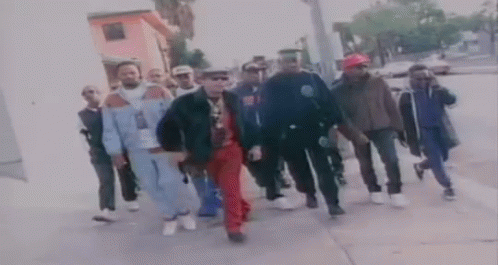 A Group Of Men Are Walking Down A Sidewalk In A Blurry Photo . GIF
