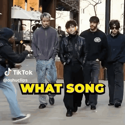 A Group Of Men Are Walking Down A Street With The Words What Song Behind Them GIF