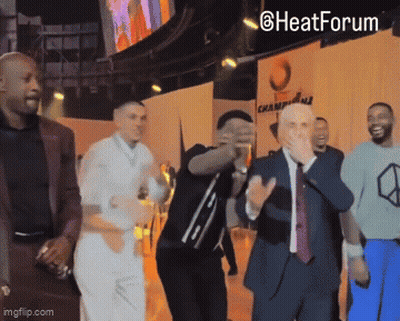 A Group Of Men Dancing In Front Of A Sign That Says Heat Forum GIF