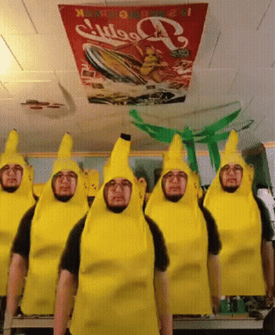 A Group Of Men Dressed As Bananas Are Standing In Front Of A Coca Cola Sign GIF