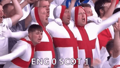 A Group Of Men Dressed As The British Flag Are Standing In A Stadium . GIF