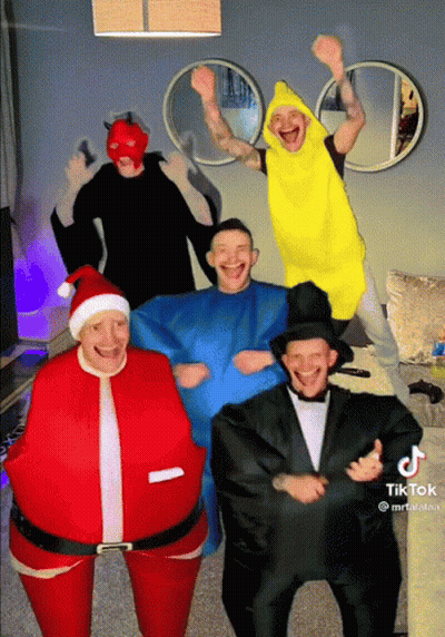 A Group Of Men Dressed In Costumes Including Santa And Banana GIF