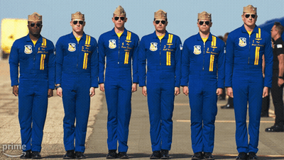 A Group Of Men In Blue Jumpsuits Are Standing In A Line With The Word Prime On The Bottom Right GIF