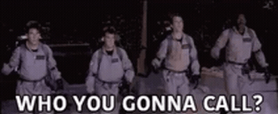 A Group Of Men In Ghostbusters Costumes Are Walking In The Dark And Talking To Each Other . GIF