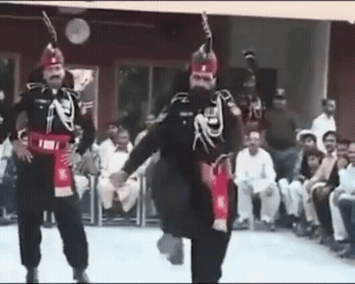 A Group Of Men In Military Uniforms Are Dancing In Front Of A Crowd Of People . GIF