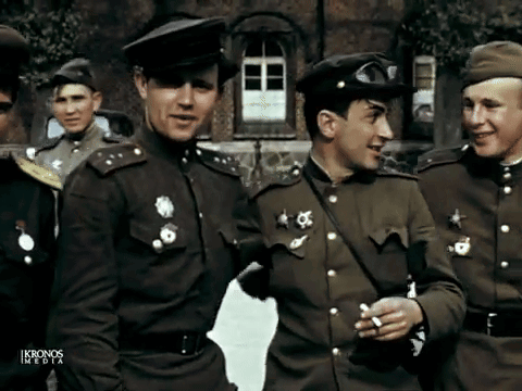 A Group Of Men In Military Uniforms Are Standing In Front Of A Building With Ikronos Media Written On The Bottom Right GIF