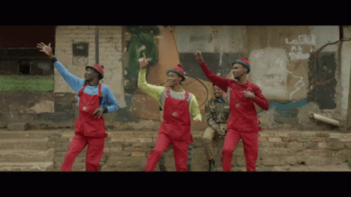 A Group Of Men In Red Overalls Are Dancing GIF