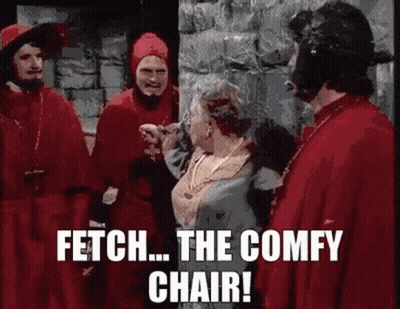 A Group Of Men In Red Robes Are Standing Next To A Woman In A Blue Dress And Talking To Her . GIF