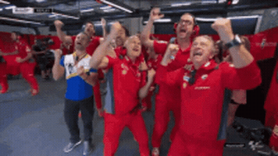 A Group Of Men In Red Uniforms Are Standing In A Room With Their Arms In The Air GIF