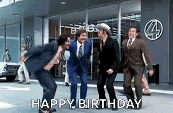 A Group Of Men In Suits And Ties Are Dancing On A Street In Front Of A Building . GIF