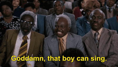 A Group Of Men In Suits And Ties Are Sitting In A Crowd And One Of Them Is Saying Goddamn That Boy Can Sing GIF