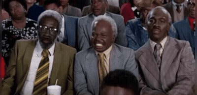 A Group Of Men In Suits And Ties Are Sitting In A Row Laughing . GIF