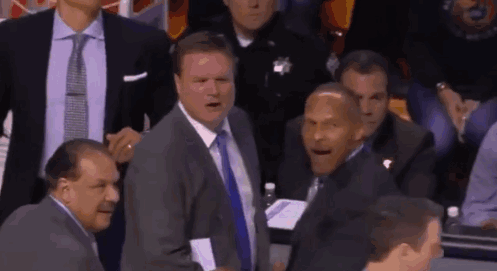 A Group Of Men In Suits And Ties Are Sitting In A Stadium Watching A Game . GIF