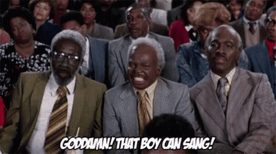 A Group Of Men In Suits And Ties Are Sitting In A Theatre Laughing . GIF