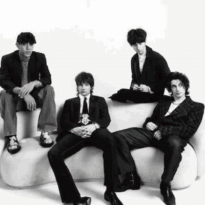A Group Of Men In Suits And Ties Are Sitting On A White Couch . GIF