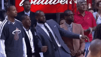 A Group Of Men In Suits And Ties Are Standing In Front Of A Budweiser Sign . GIF