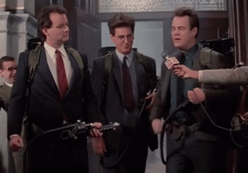 A Group Of Men In Suits And Ties Are Standing Next To Each Other In A Hallway . GIF